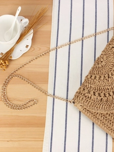 Handmade khaki crochet shoulder bag with gold chain strap on a wooden table setup