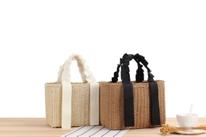 Straw woven handbags with ribbon handles displayed on wood table for summer
