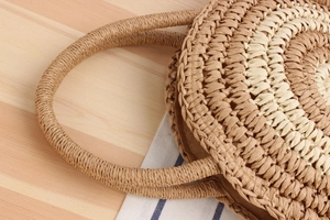 Détail d'un sac rond en paille tissé à la main avec rayures, anse et doublure