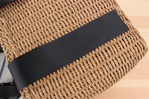 Macro detail of brown woven paper rope bag with a decorative black grosgrain ribbon