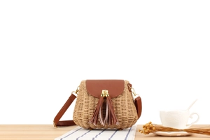 Détail du sac à bandoulière en papier tressé avec pompons et poignée en cuir brun
