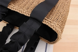 Detail of woven straw tote bag featuring black grosgrain handles and inner lining