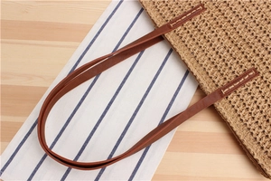 Close-up of natural straw weave texture and brown leather handle on a minimalist tote bag