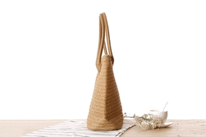 Detail shot of the textured paper rope weaving and smooth leather handle of the tote bag
