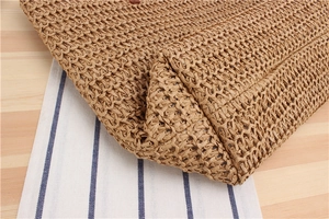 Detailed macro view of reinforced hand-woven base and texture on raffia straw tote bag