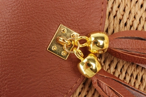 Détail macro de franges en cuir marron avec clous dorés sur un sac tissé chic
