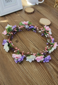 Detail view of handmade flower crown with pink, purple and white silk petals on brown vine