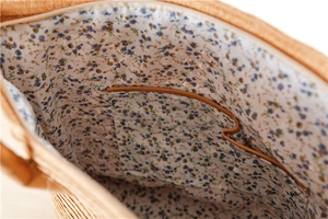 Detail of paper straw bag interior featuring floral lining and zippered inner pocket