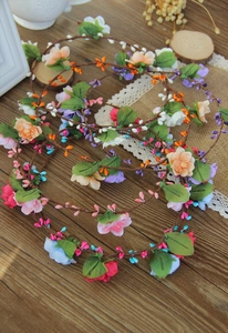 Detail of floral bridal headband with colorful artificial flowers and green leaves on wood
