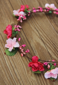 Close-up of handmade floral headband with pink silk roses on a woven brown base