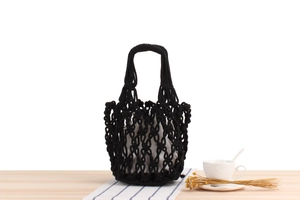 Detail of hand-woven black cotton rope mesh bag with a cream drawstring inner pouch