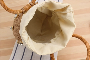 Top view of woven straw bucket bag showing spacious canvas lining and crystal accents