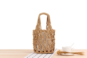 Detail of hollow woven cotton bucket bag with white drawstring liner on wooden table