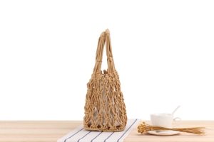Detail of hand-woven cotton net bag with white fabric lining on a wooden table