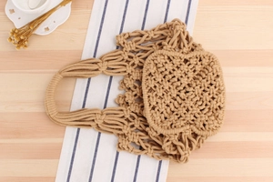 Close-up of beige macrame woven tote bag with hollow out design and integrated handle