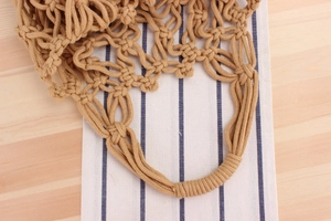 Detail of camel crochet knit tote bag showing woven handles and hollow knot pattern