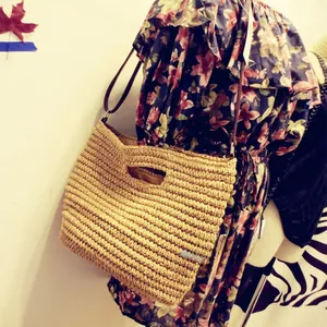 Detail of paper straw woven bag featuring a wavy texture and brown leather strap