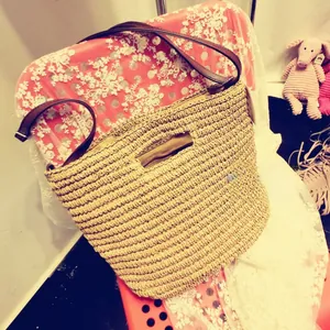 Detailed view of woven paper rope texture and brown leather strap on a summer tote
