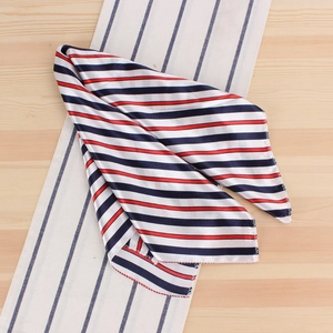 Détail d'un carré de soie satiné à rayures marine, blanc et rouge sur fond bois
