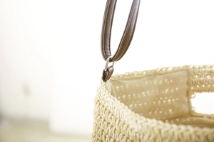 Detailed macro view of beige paper rope weave texture and brown leather strap connector