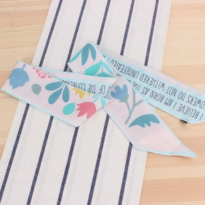 Vue détaillée d'un foulard en soie bleu clair avec imprimés floraux et texte anglais