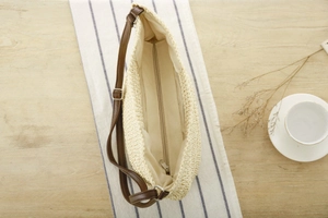 Detail of paper rope woven bag featuring adjustable brown strap and secure silver zipper