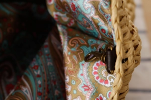 Gros plan sur la boucle en bronze et la doublure paisley du sac tissé