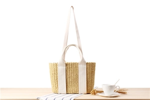 Macro detail of hand-woven straw tote bag with canvas straps on a minimalist wooden table