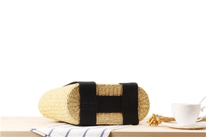 Detail of woven straw handbag base with black canvas H-shaped crisscross straps