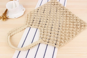 Detail of hollow woven paper rope handbag with braided handle on a rustic table