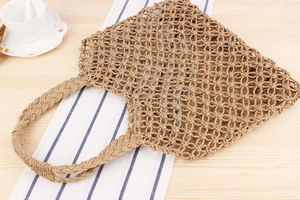 Close-up of handmade hollow paper rope woven tote bag on a rustic wooden table