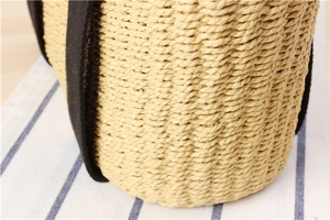 Detailed macro view of beige straw woven texture and contrasting black fabric strap
