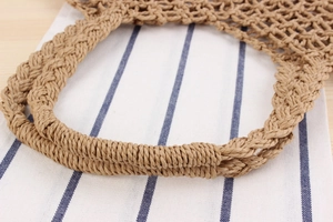 Detailed close-up of khaki woven paper rope handbag showing thick handles and hollow grid