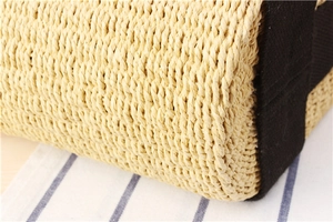 Close-up of woven straw tote bag featuring black canvas strap trim and textured pattern