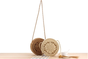 Detailed view of handmade circular straw bags in brown and cream with floral weave