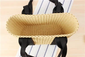 Top view of a large capacity woven straw tote bag with black canvas handles for beach trips