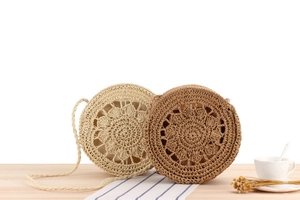 Detail of round straw crossbody bags featuring hollow floral crochet and woven straps