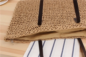 Close-up of top zipper closure and woven texture on casual straw tote bag