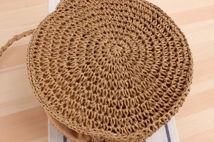 Detailed close-up of a handmade round straw bag with intricate woven texture and strap