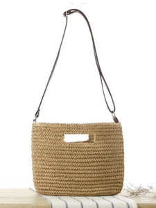 Straw woven crossbody bag with top handle on wooden table for summer vacation