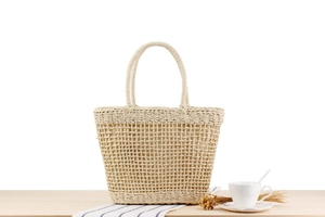 Close-up of cream woven straw bag featuring hollow mesh pattern and circular handles