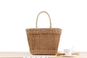 Detail view of a natural woven paper rope tote bag featuring a textured hollow grid design