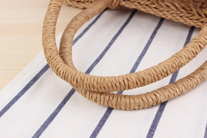 Detailed macro view of sturdy woven grass tote handle with natural fiber spiral texture