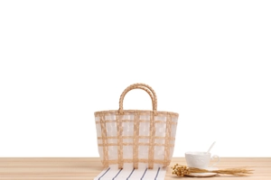 Detail of checkered woven tote bag with round handles on a light wooden table