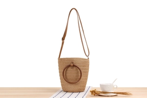 Dettaglio della borsa a secchiello in corda di carta beige con manici in legno marrone