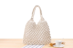 Detail of hand-woven off-white cotton rope tote bag with hollow diamond knit patterns