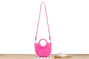 Detail of hot pink woven semicircular beach bag with handle and crossbody strap