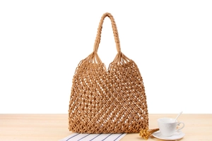 Detail of hand-woven macrame tote bag featuring reinforced knotted handles and mesh texture