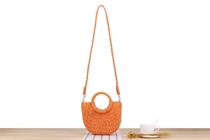 Detailed macro view of orange woven straw handbag texture and metal shoulder strap hooks