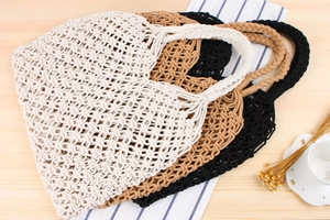 Close-up of four colorful woven mesh bags in cream, khaki, brown and black on a wooden table